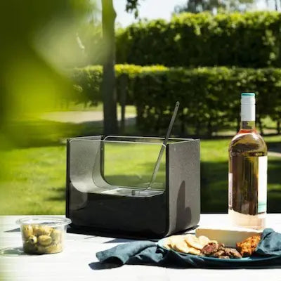 Rectangular bio ethanol tabletop fireplace outdoors on a garden table with wine and snacks